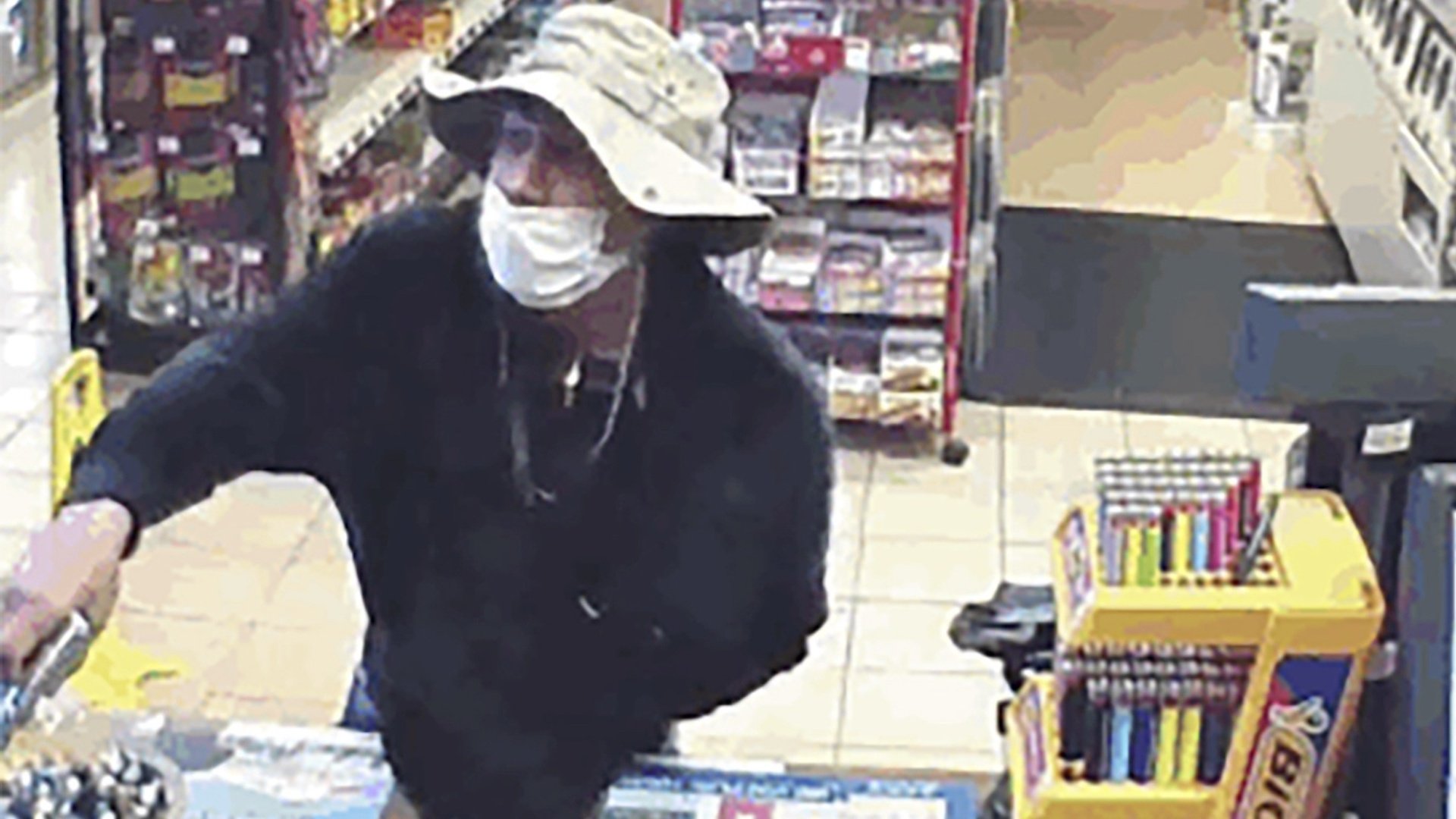 This March 26, 2020 image from surveillance video shows a man, believed to be William Rosario Lopez wearing a surgical mask, with a gun in a Connecticut convenience store. Reports are starting to pop up across the country, as well as in other parts of the world of crimes that were pulled off in no small part because so many of us are wearing masks. (U.S. District Court of Connecticut via AP)
