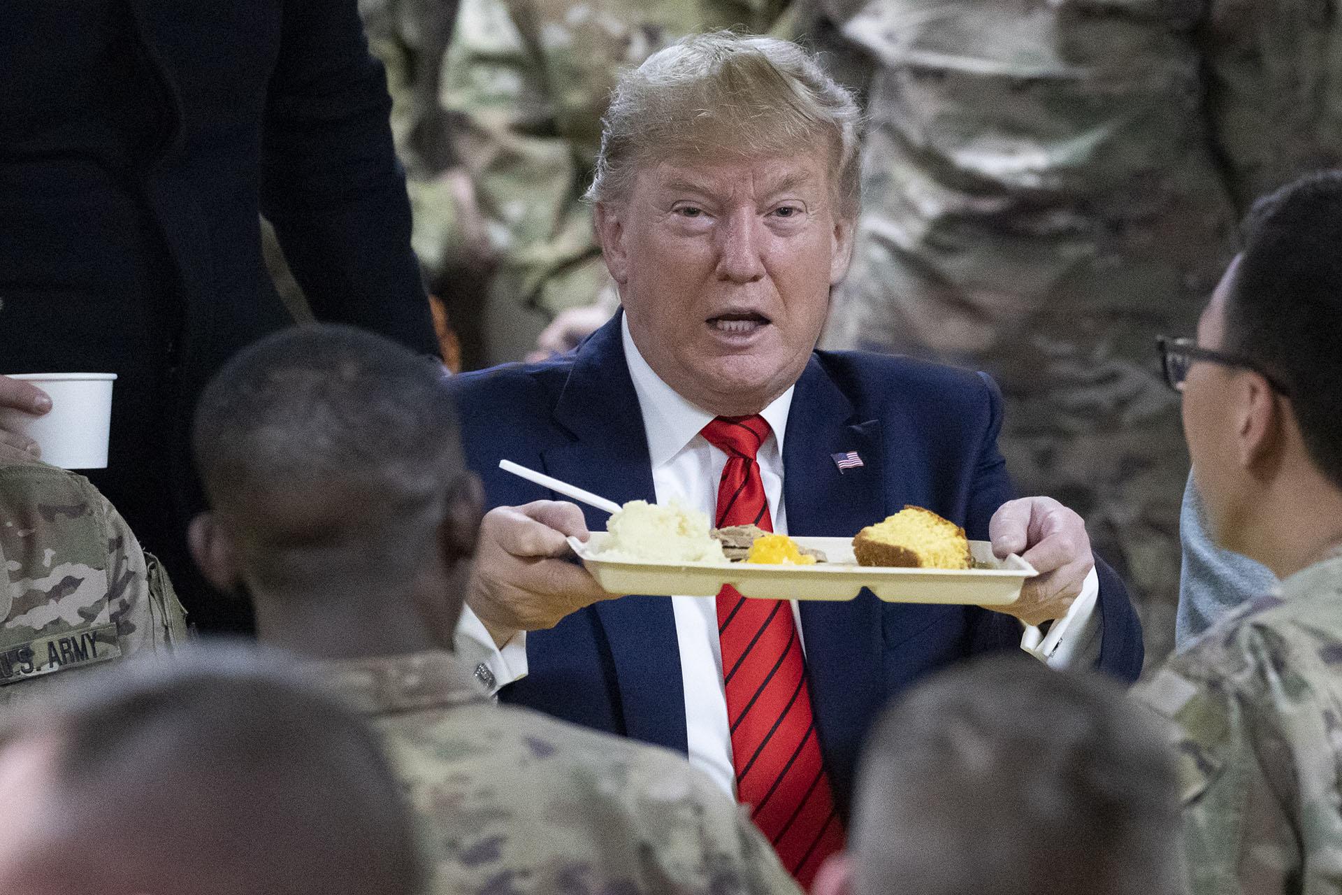 President Donald Trump holds up a tray of Thanksgiving dinner during a surprise Thanksgiving Day visit to the troops, Thursday, Nov. 28, 2019, at Bagram Air Field, Afghanistan. (AP Photo / Alex Brandon)