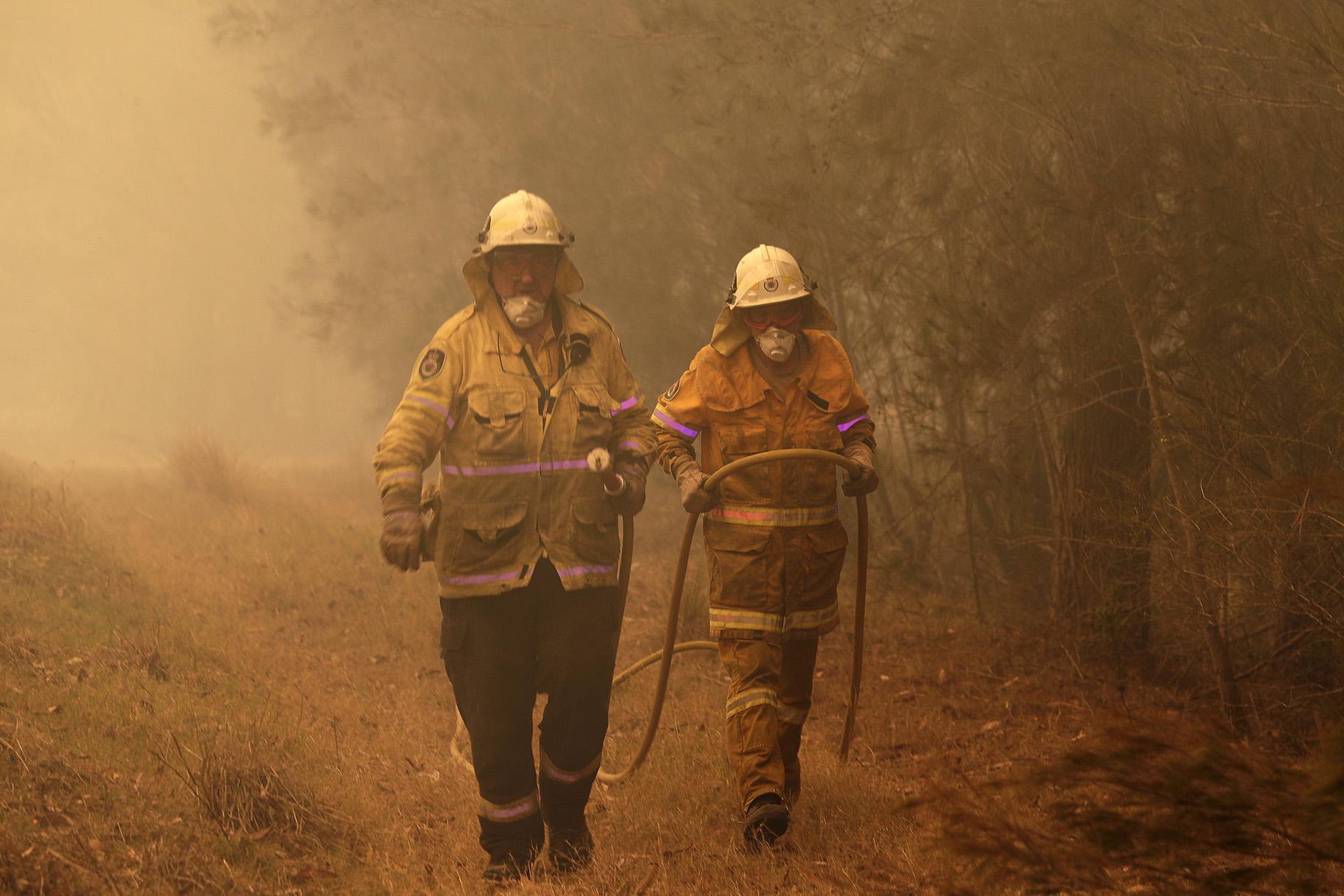 Firefighters drag their water hose after putting out a spot fire near Moruya, Australia, Saturday, Jan. 4, 2020. Australia’s Prime Minister Scott Morrison called up about 3,000 reservists as the threat of wildfires escalated Saturday in at least three states with two more deaths, and strong winds and high temperatures were forecast to bring flames to populated areas including the suburbs of Sydney. (AP Photo / Rick Rycroft)