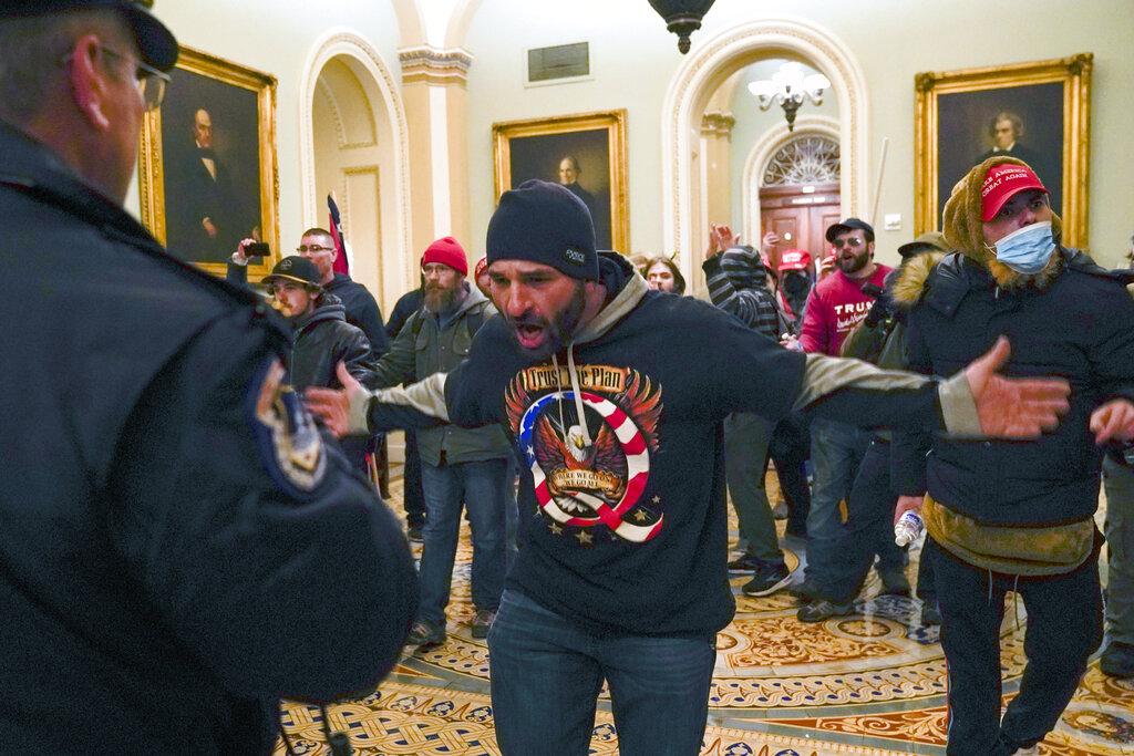 Trump supporters gesture to U.S. Capitol Police in the hallway outside of the Senate chamber at the Capitol in Washington, Wednesday, Jan. 6, 2021. (AP Photo / Manuel Balce Ceneta)