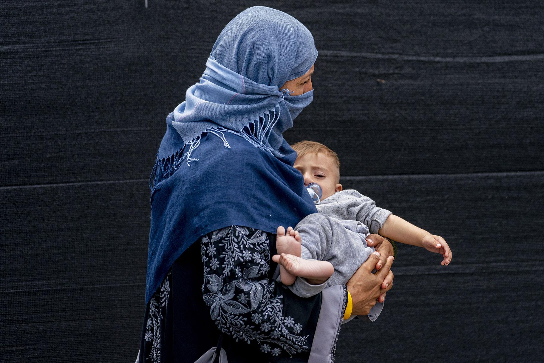 A woman evacuated from Afghanistan steps off a bus with a baby as they arrive at a processing center in Chantilly, Monday, Aug. 23, 2021, after arriving on a flight at Dulles International Airport. (AP Photo / Andrew Harnik)