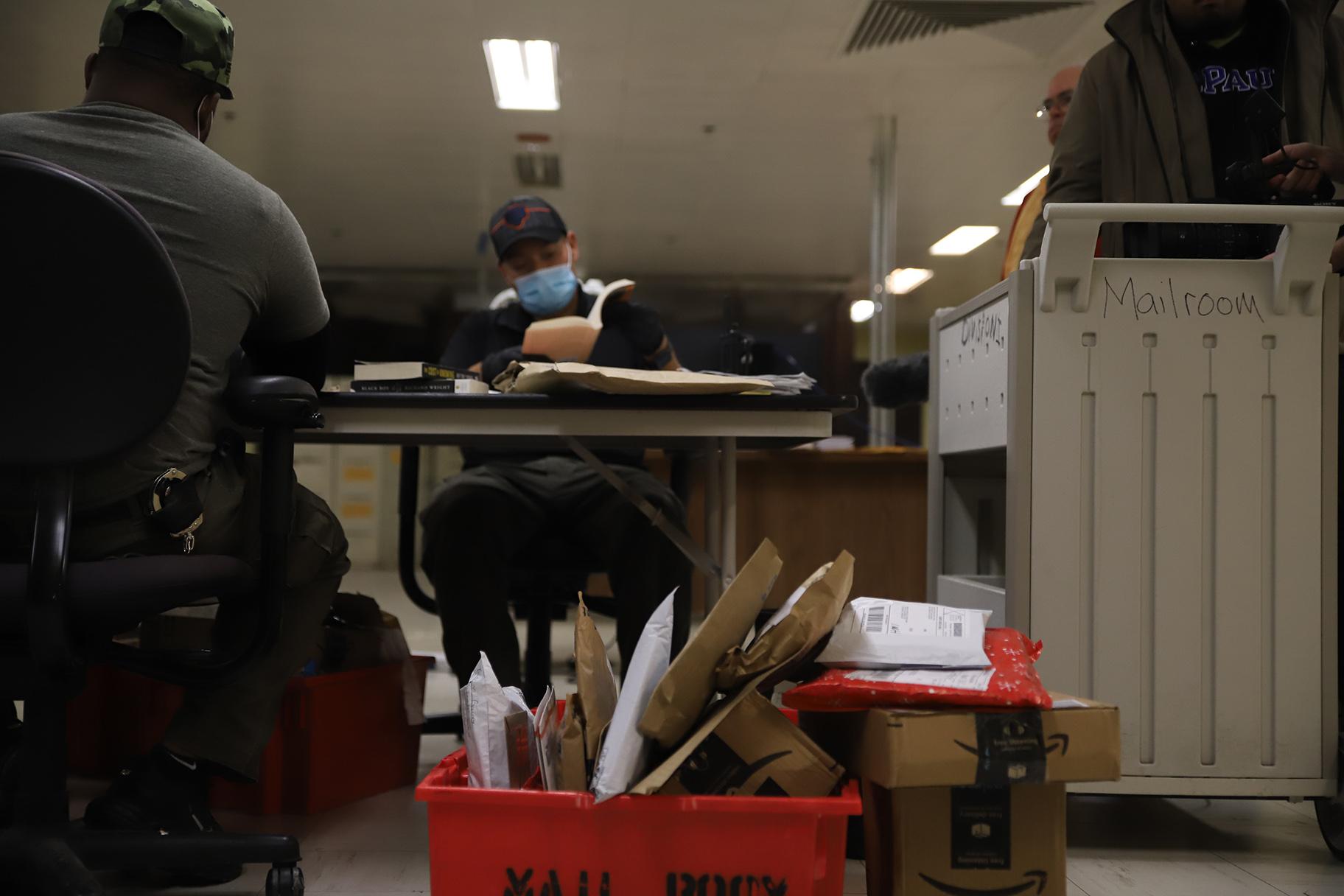 A group of jail personnel sniff, touch and pass around stacks of letters and books in the mail room at Cook County Jail to check for paper soaked in drugs on Oct. 12. All mail coming into the jail has faced greater screening methods since the paper restriction began in April. (Cary Robbins / DePaul) 