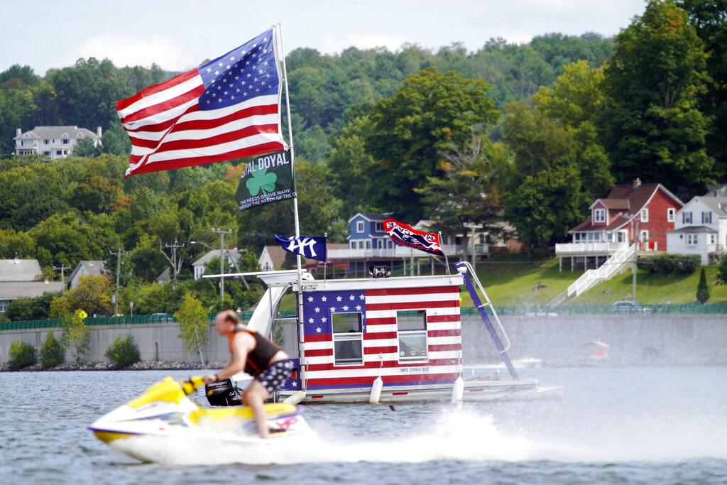A jet skier passes a patriotic shanty-boat owned by AJ Crea on Pontoosuc Lake on Labor Day in Pittsfield, Mass., Monday, Sept. 7, 2020. (Ben Garver / The Berkshire Eagle via AP)