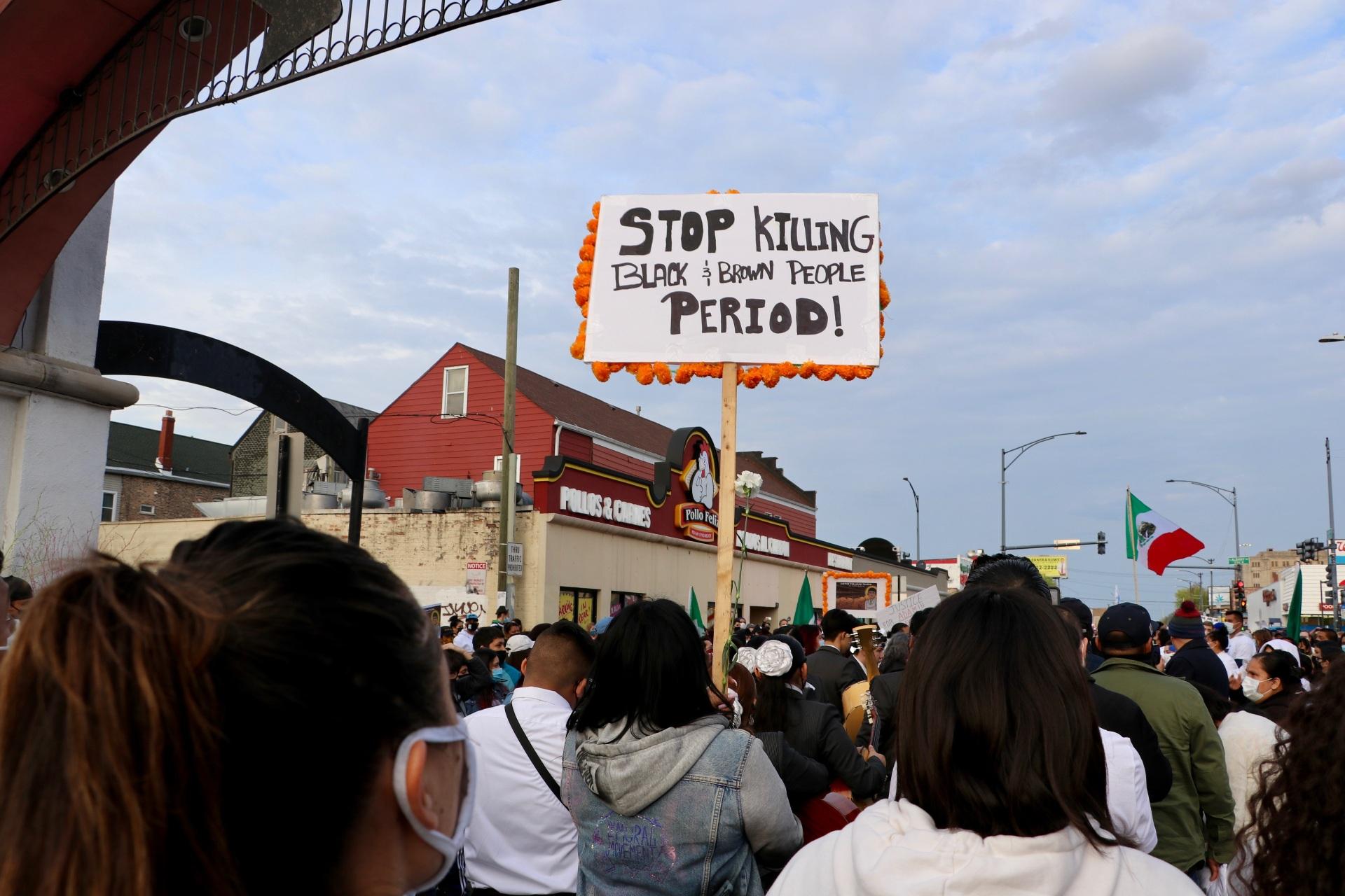A protester holds a sign reading “Stop Killing Black & Brown People, Period!” while marching at the Adam Toledo peace walk held in Chicago’s Little Village on April 18, 2021. (Evan Garcia / WTTW News)