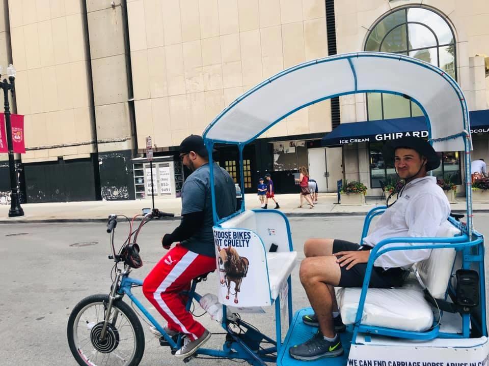 A Pedicab Ride Guys employee drives a passenger in a pedicab covered with advertisements from the Chicago Alliance for Animals. (Marla Rose / Facebook)