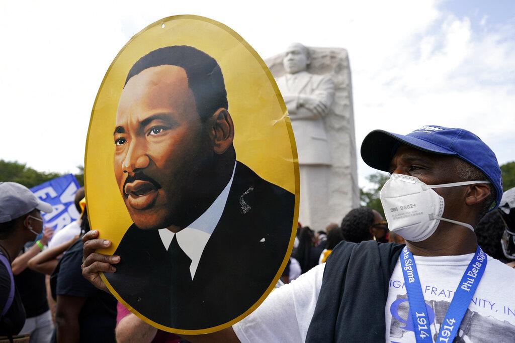 A man holds a photo of Martin Luther King, Jr., at the Martin Luther King Jr. Memorial during the March on Washington, Friday Aug. 28, 2020, in Washington. (AP Photo / Carolyn Kaster)
