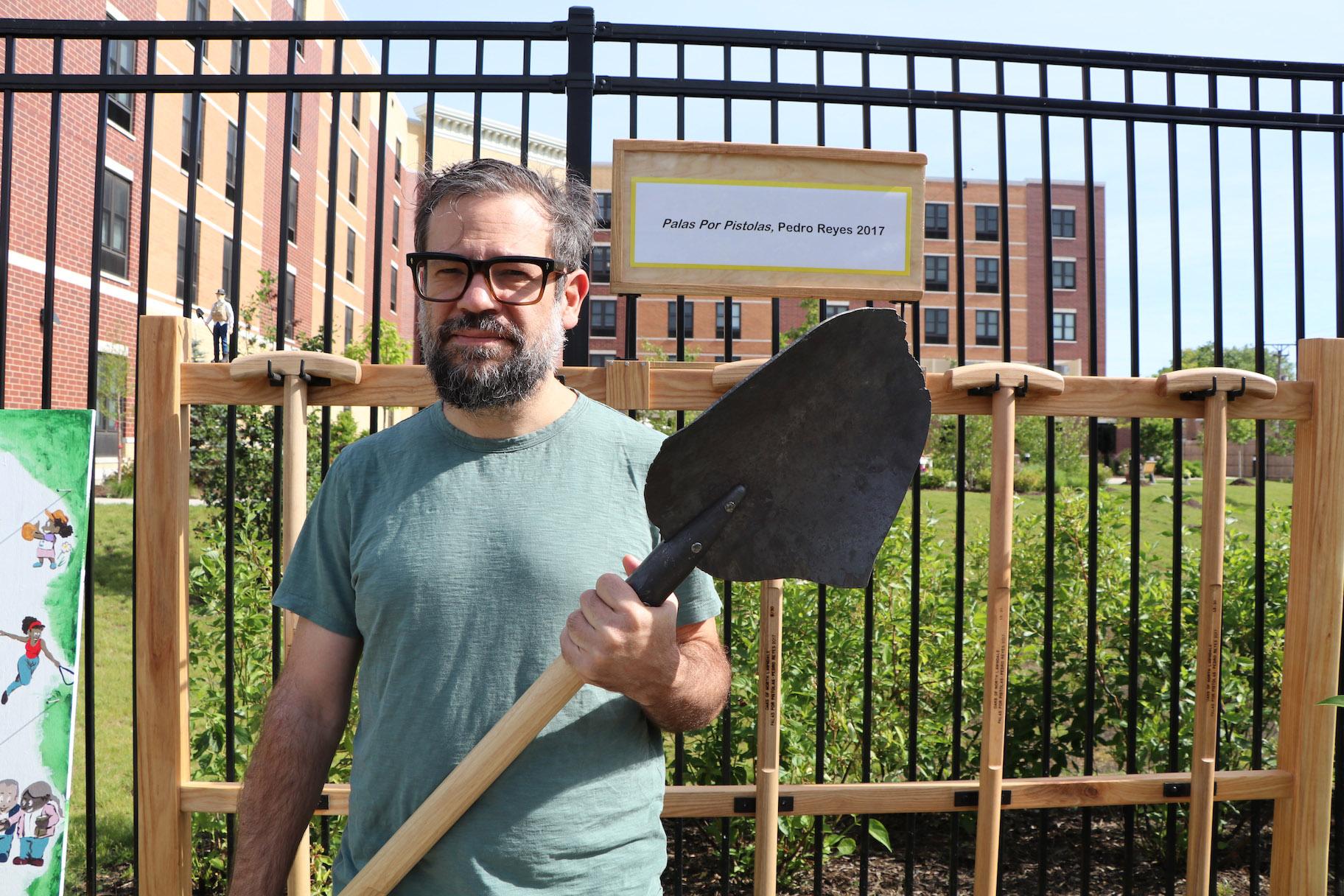Mexican artist Pedro Reyes holds a shovel that’s part of his “Palas por Pistolas” collection. The shovel’s head is made from melted guns. (Evan Garcia / WTTW)