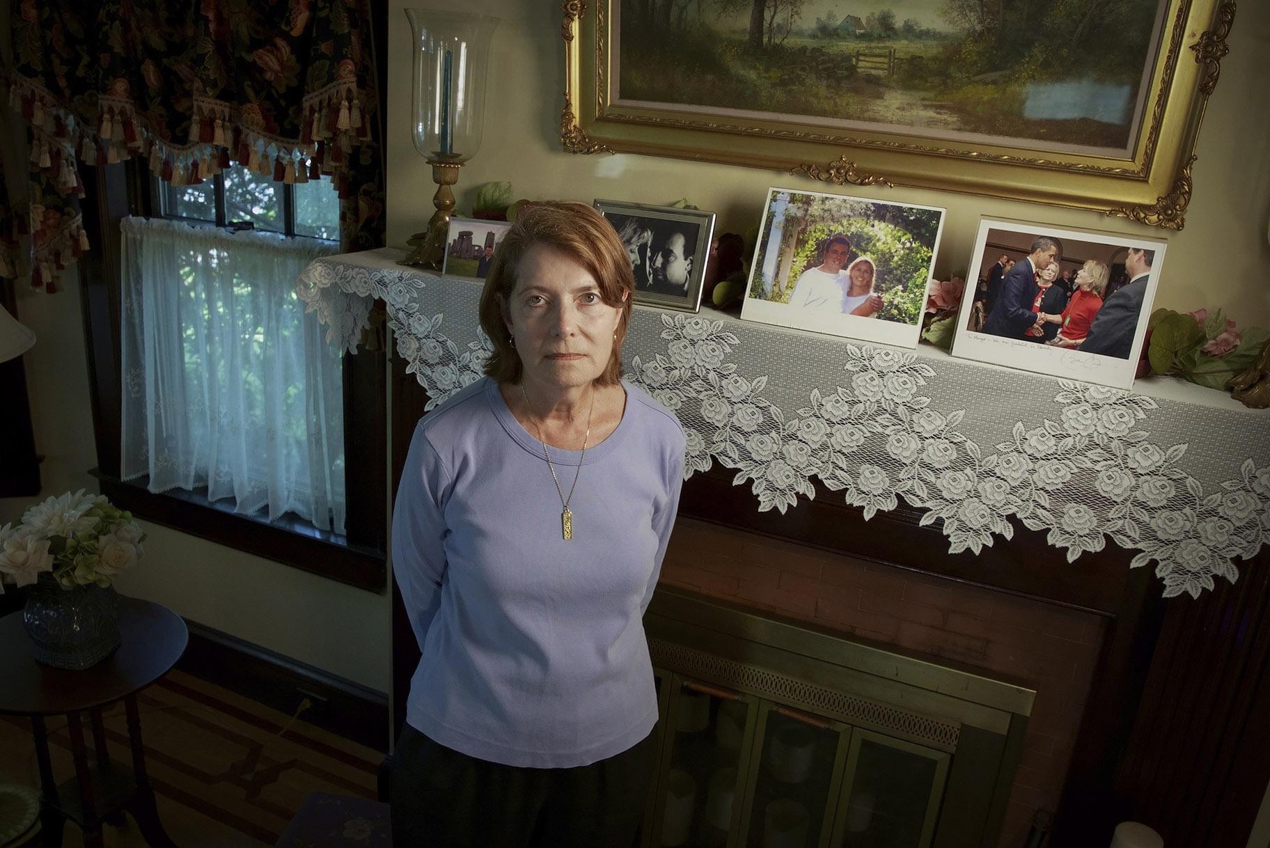 Margot Eckert stands by a display of pictures of her brother-in-law Sean Rooney and sister Beverly Eckert at her home, Thursday, July 15, 2021, in Springfield, Mass. (AP Photo / Robert Bumsted)