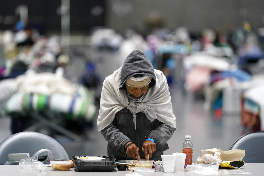 A woman eats at a homeless shelter inside the San Diego Convention Center Tuesday, Aug. 11, 2020, in San Diego. (AP Photo / Gregory Bull)