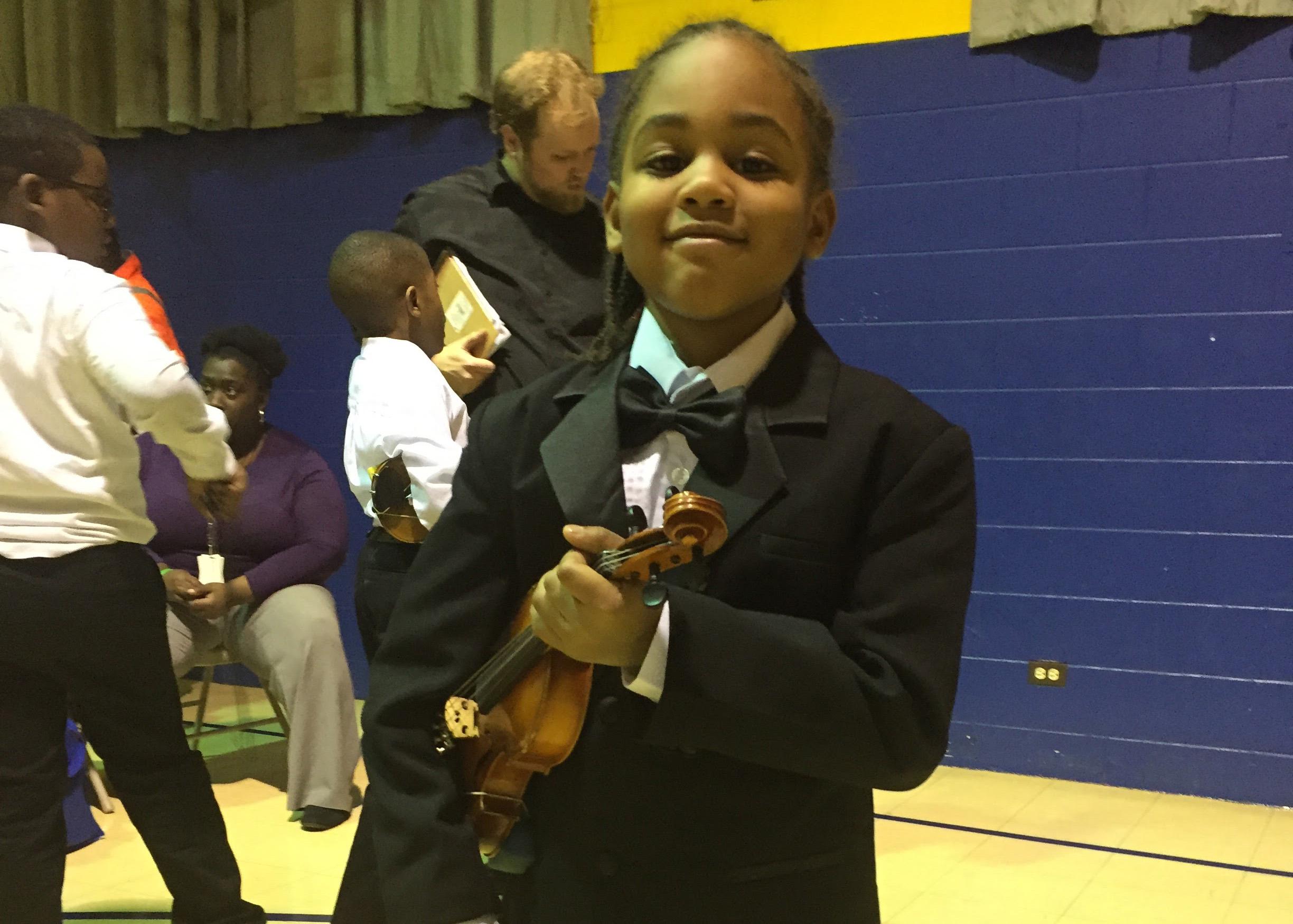 A student clutches his violin at a M.U.S.I.C. Inc performance. (Courtesy of Sarah Dupuis) 