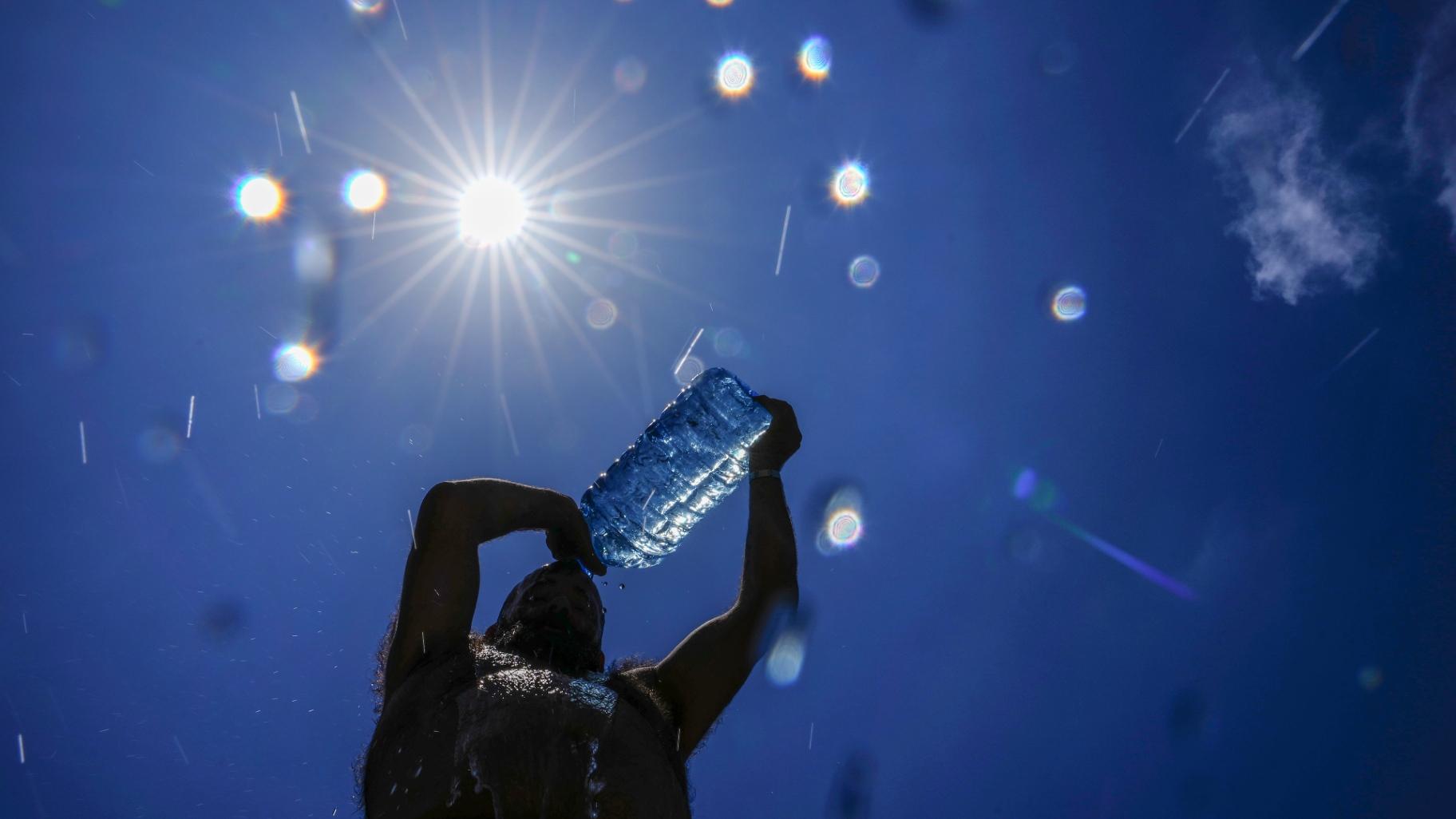 FILE - A man pours cold water onto his head to cool off on a sweltering hot day in the Mediterranean Sea in Beirut, Lebanon, July 16, 2023. (Hassan Ammar / AP Photo, File)