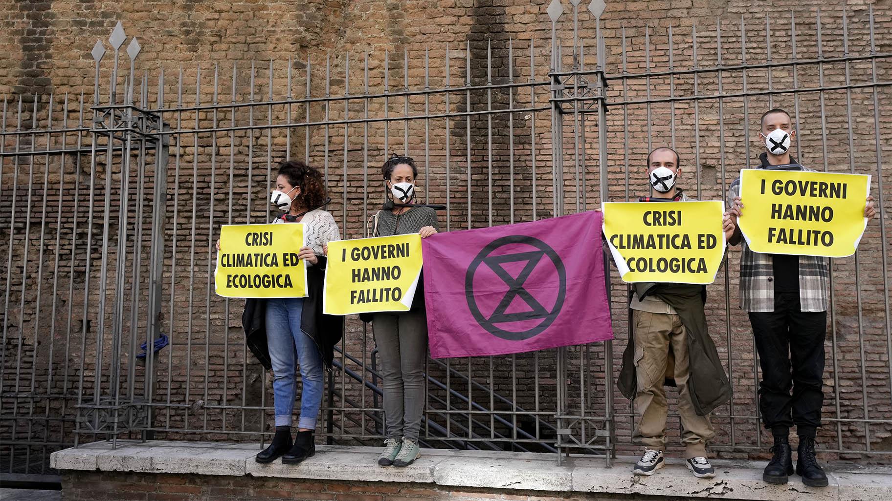 Activists from Extinction Rebellion use bike locks to chain themselves to a fence while holding signs during a demonstration outside the G20 summit in Rome, Sunday, Oct. 31, 2021.  (AP Photo / Luca Bruno)