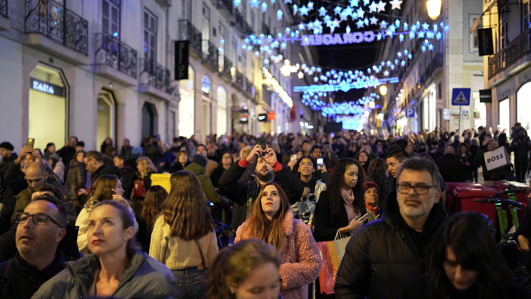 People look up at Christmas lights as crowds stroll around downtown Lisbon's Chiado neighborhood, Saturday evening, Dec. 23, 2023. (AP Photo / Armando Franca)