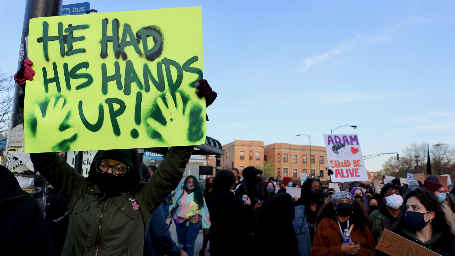 Protester Natalia Sustaita holds a sign reading “He Had His Hands Up!” at a Logan Square protest April 16, 2021, over the fatal police shooting of 13-year-old Adam Toledo. (Evan Garcia / WTTW News)