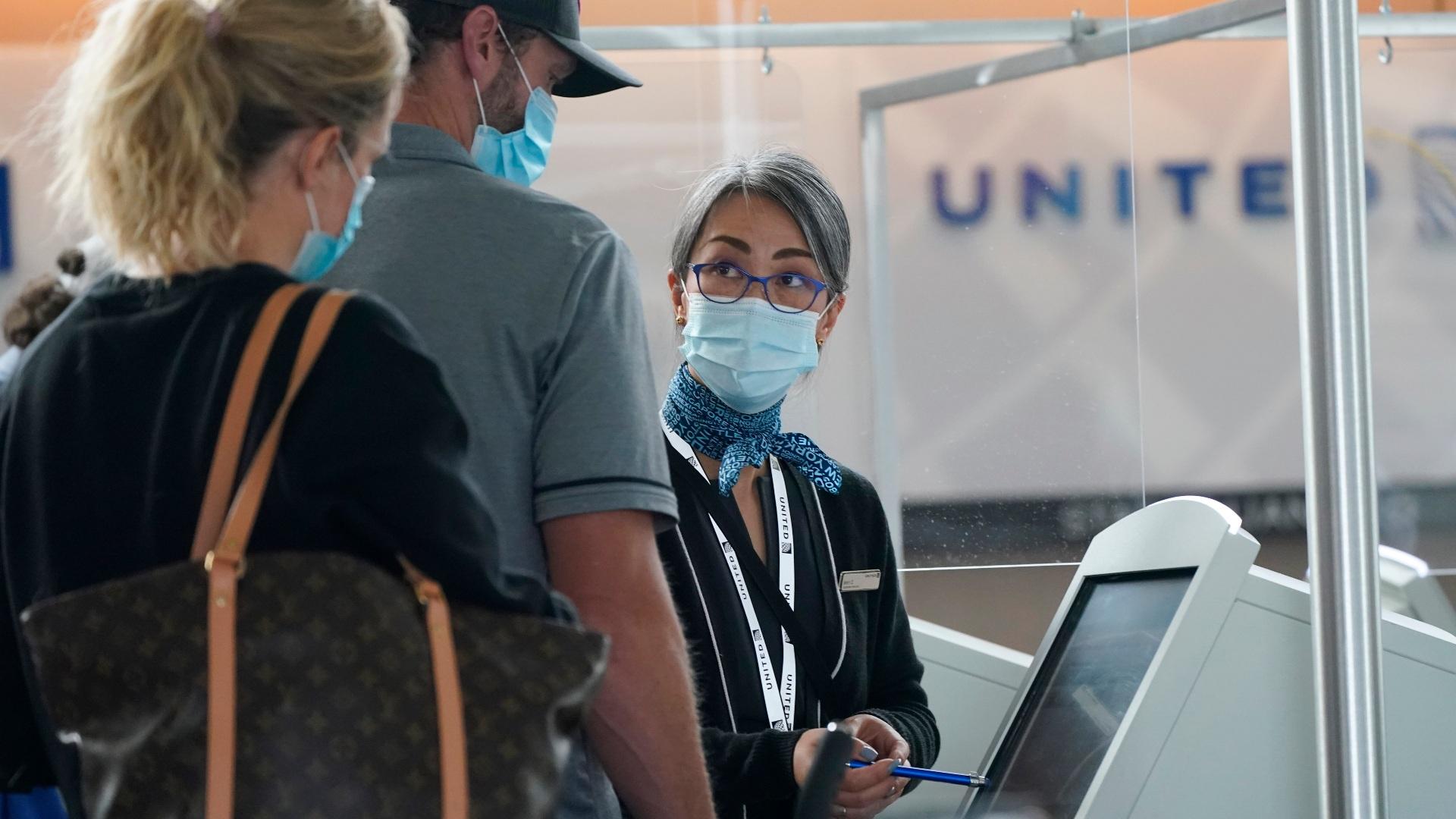 Travelers check in at a United Airlines kiosk with help from a United employee in the main terminal of Denver International Airport Thursday, Oct. 1, 2020, in Denver. (AP Photo / David Zalubowski)