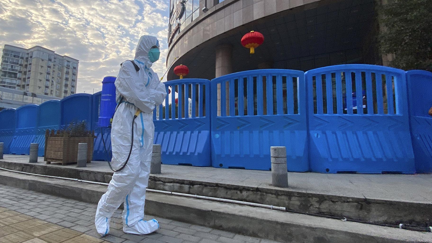 A worker in protectively overalls and carrying disinfecting equipment walks outside the Wuhan Central Hospital, China on Feb. 6, 2021. (AP Photo / Ng Han Guan, File)