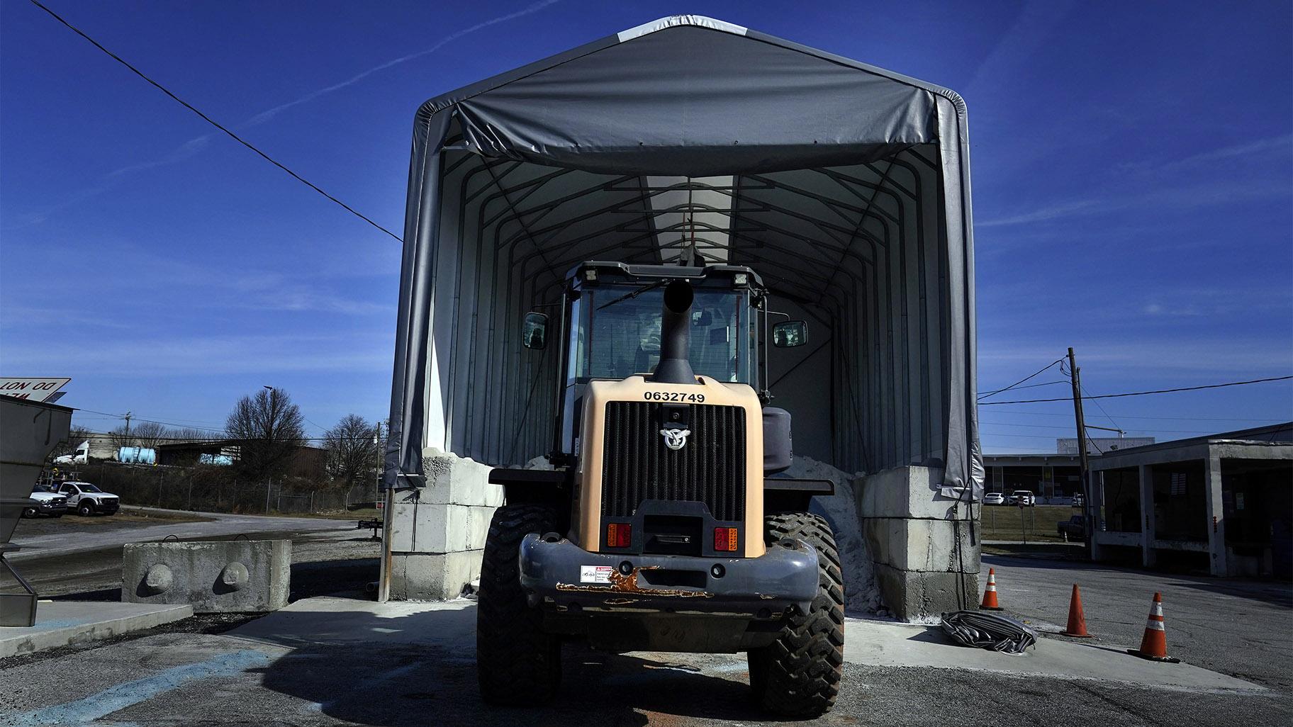 A tractor sits in front of a pile of salt used to create a brine that will help clear road of ice and snow ahead of a winter storm at the GDOT's Maintenance Activities Unit location on Friday, Jan. 14, 2022, in Forest Park, Ga. (AP Photo / Brynn Anderson)