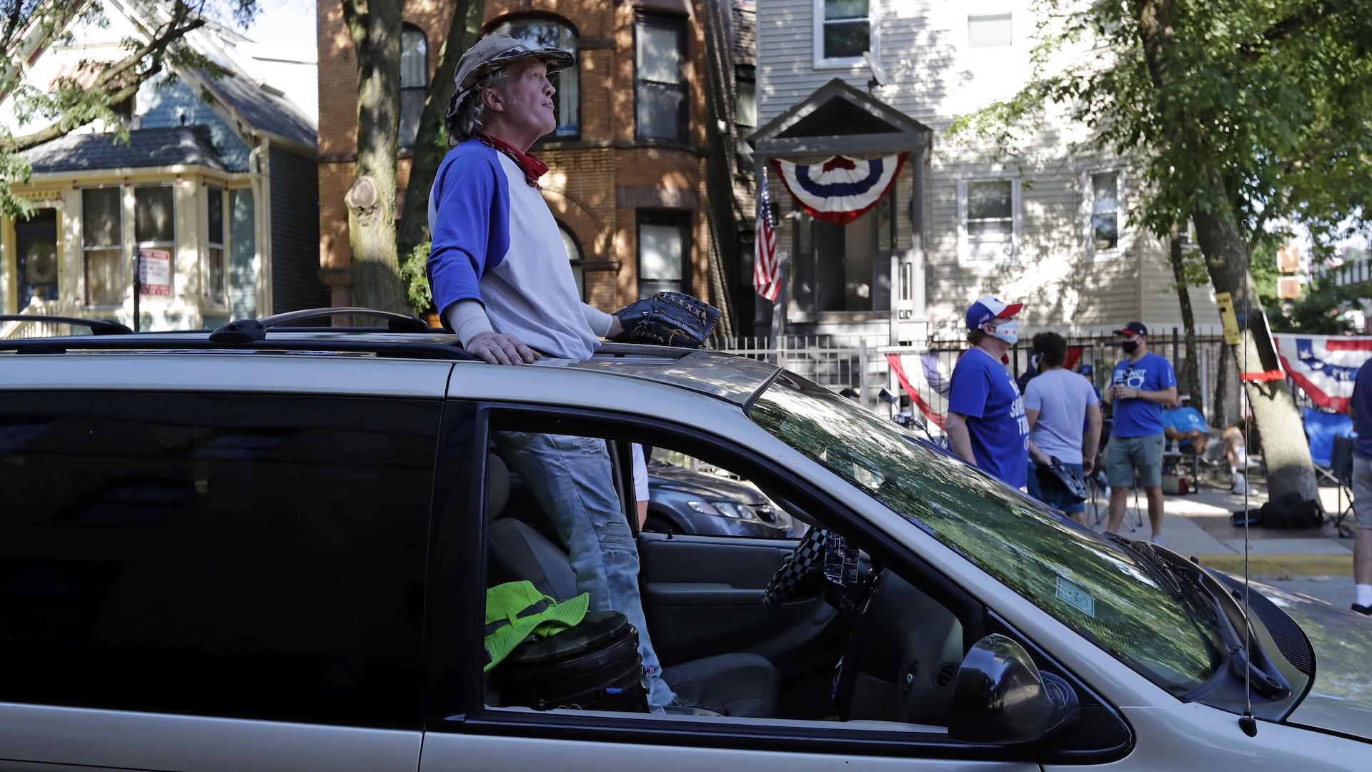 Chicago Cubs fans wait for a ball outside of Wrigley Field before the Opening Day baseball game between the Chicago Cubs and the Milwaukee Brewers in Chicago, Friday, July 24, 2020, in Chicago. (AP Photo / Nam Y. Huh)