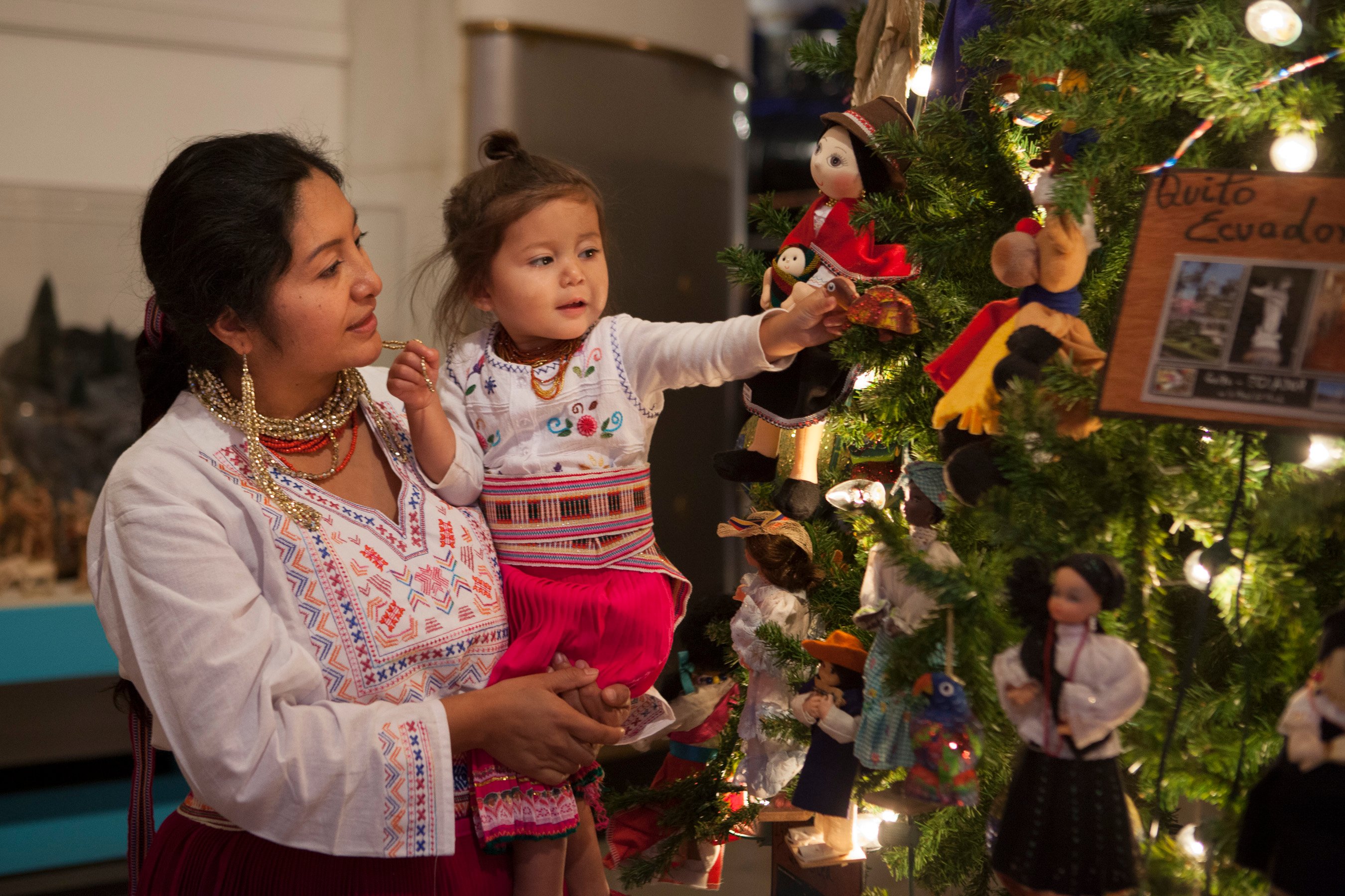 Volunteers, dressed in traditional Ecuadorian clothing, decorate the tree of Ecuador. (J.B. Spector, Museum of Science and Industry)