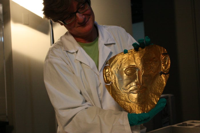 Angeliki Kossyva, an archeologist at the Museum of Mycenae, holds up a reproduction of the Mask of Agamemnon (Chloe Riley)