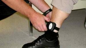 An individual being fitted with an electronic ankle bracelet. Courtesy of WORLD Law Direct.