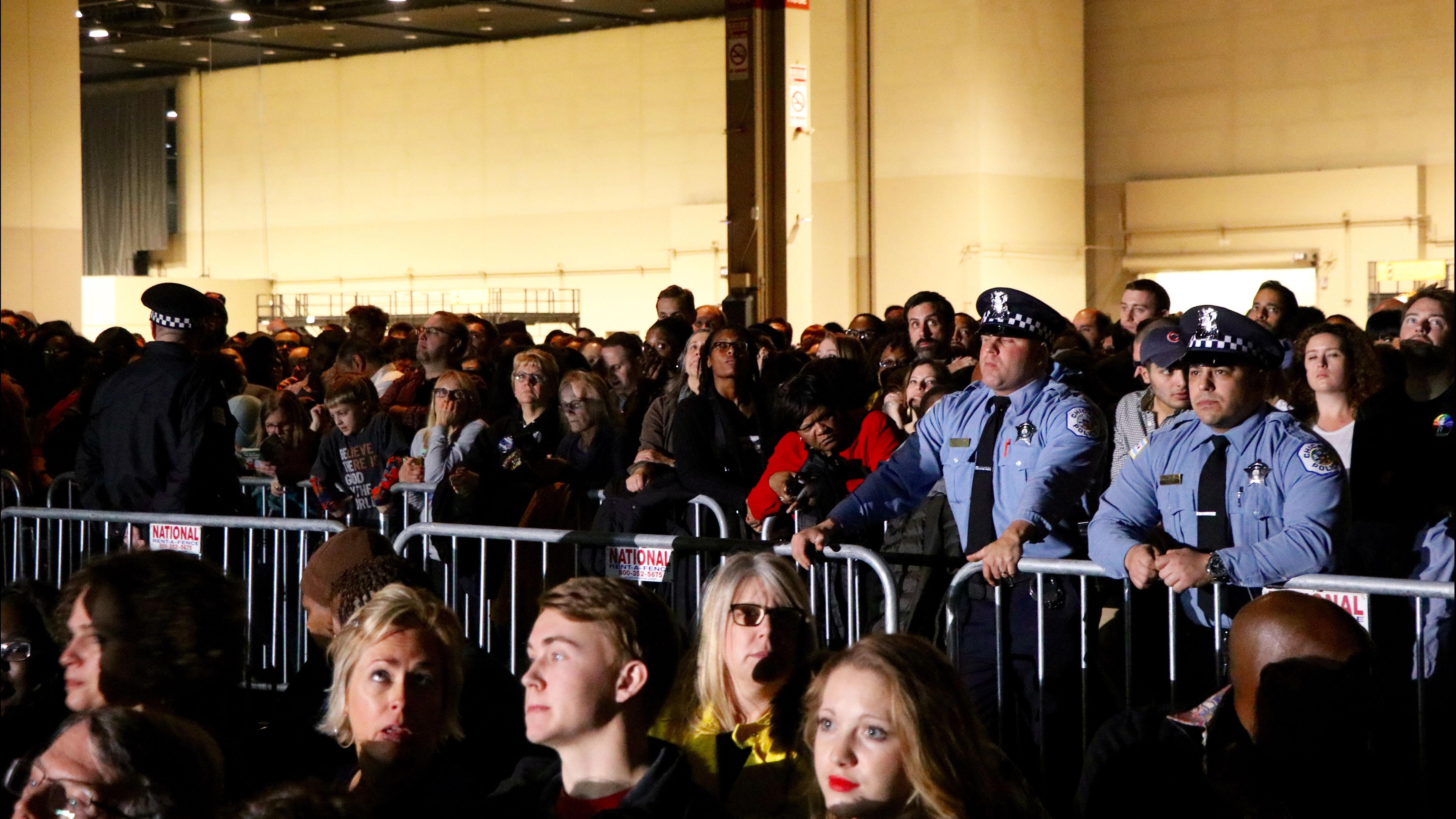 Attendees and two police officers waiting before the opening act begins. (Evan Garcia / Chicago Tonight)