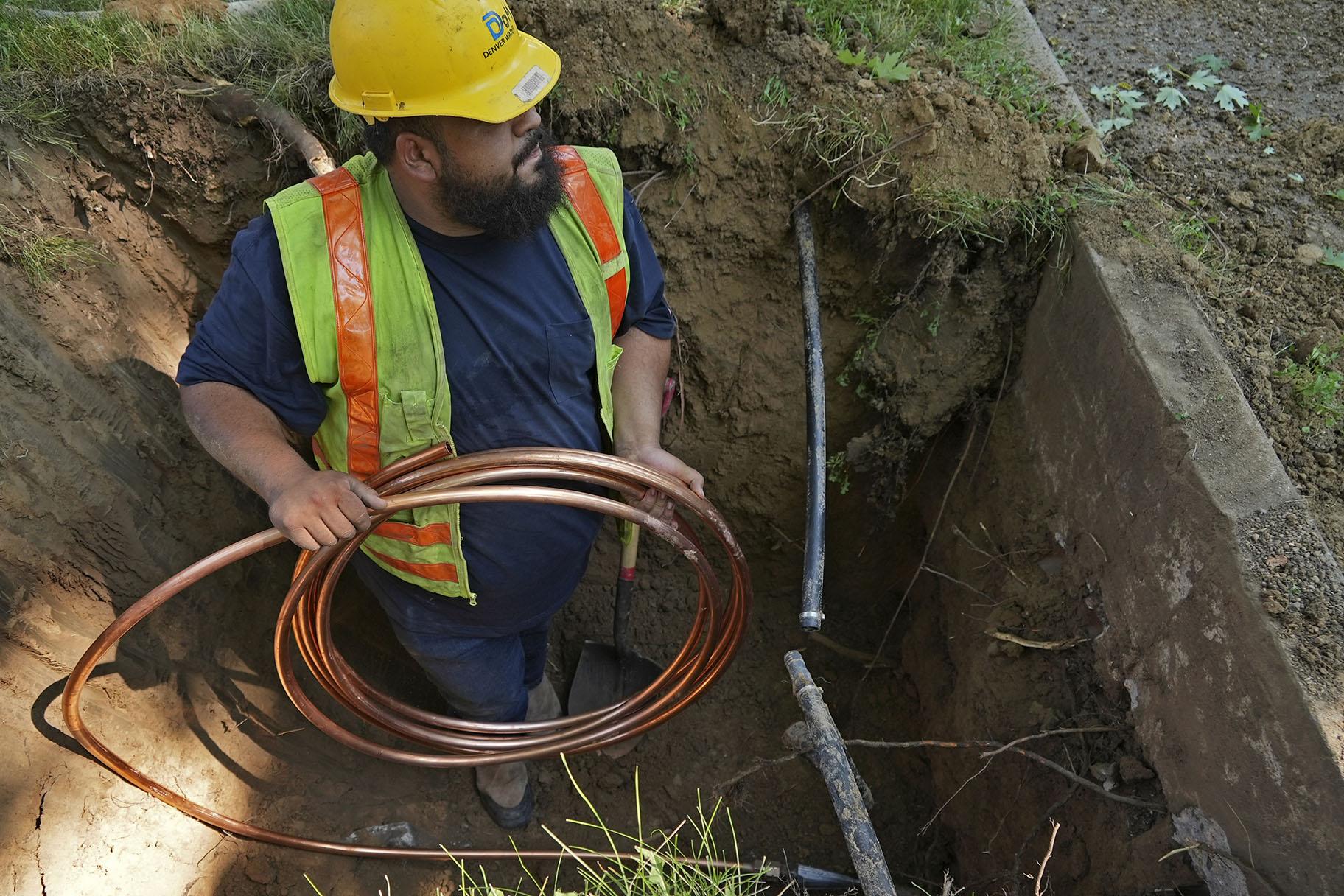 A worker with Denver Water prepares to pass a new copper water service line from a residential water meter to the water main on Thursday, June 17, 2021, in Denver. (AP Photo / Brittany Peterson)