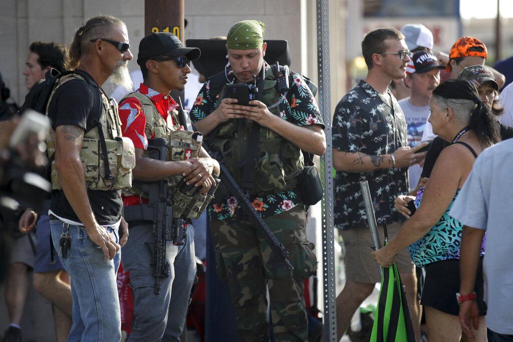 In this June 20, 2020 file photo, gun-carrying men wearing Hawaiian print shirts associated with the boogaloo movement watch a demonstration near where President Trump had a campaign rally in Tulsa, Okla. (AP Photo / Charlie Riedel, File)