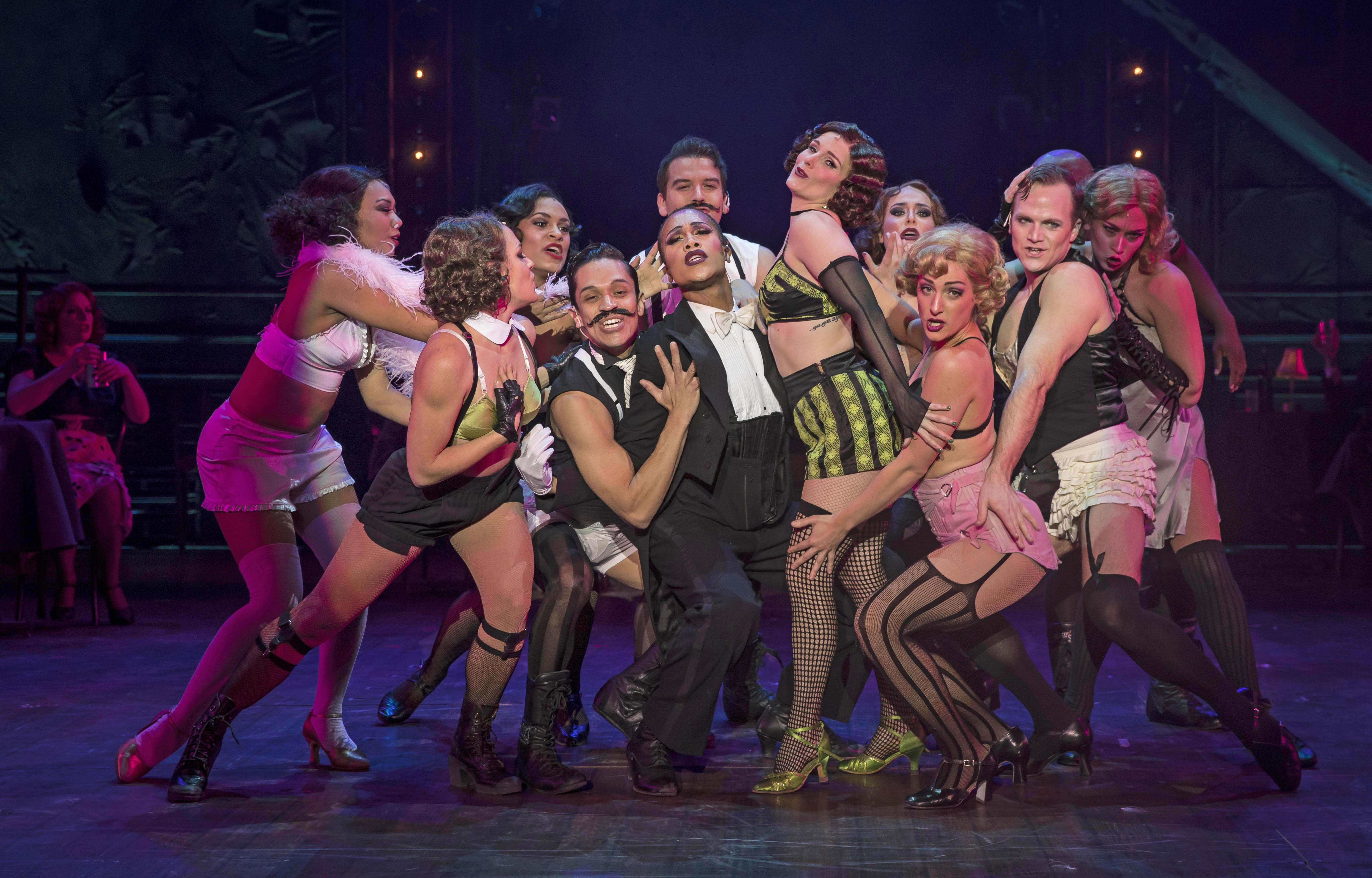 Joseph Anthony Byrd (center, tux) plays the Emcee and Kelly Felthous (black and green striped shorts) plays Sally Bowles in Paramount Theatre’s “Cabaret.” (Credit: Liz Lauren)