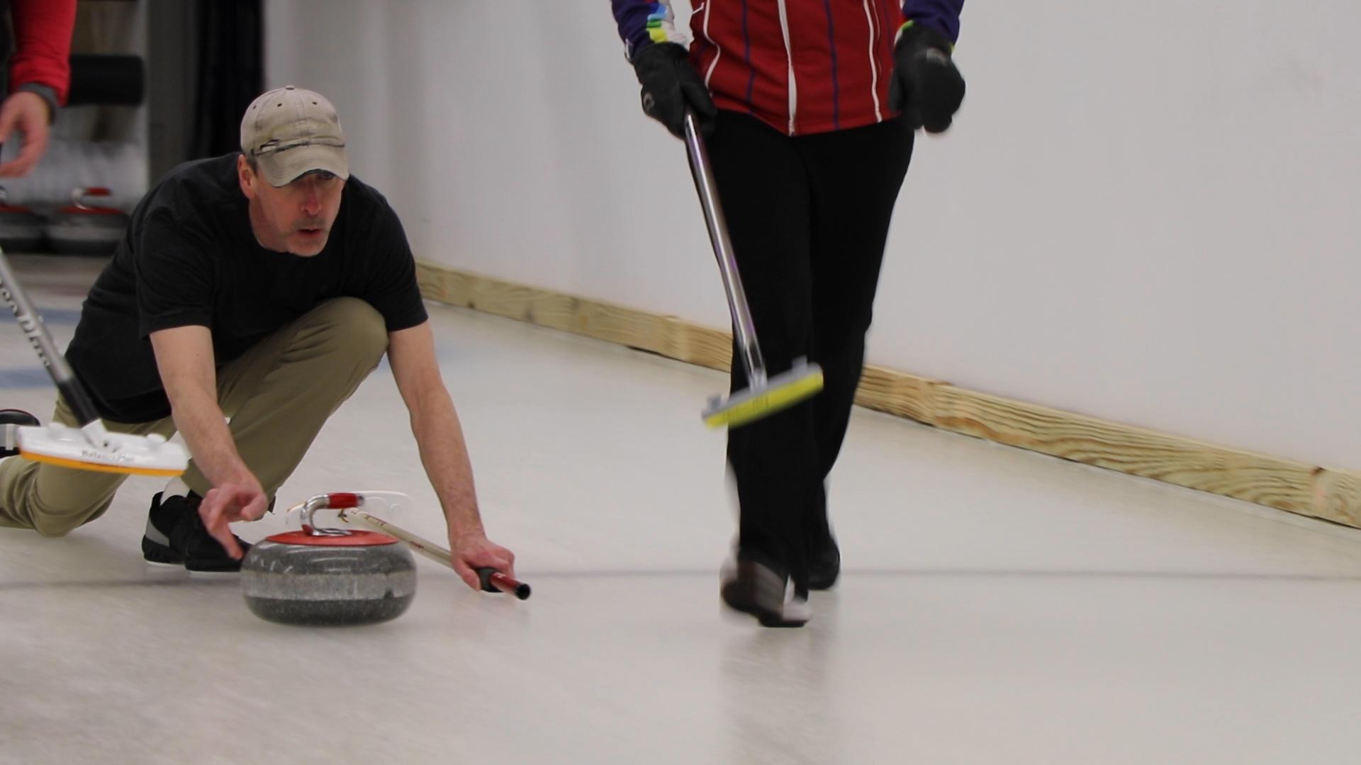 A shooter sends the 42-pound granite curling stone down the sheet of ice. (Evan Garcia / WTTW News)