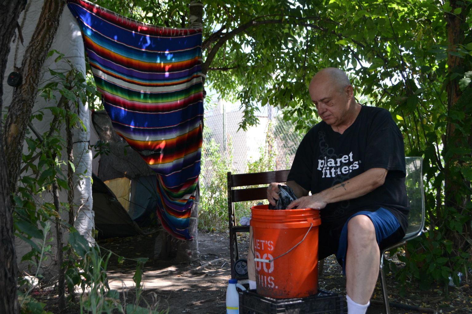 Don Gorobegko washes clothes Friday, Aug. 10, 2018, in a homeless encampment along DesPlaines Street. (Kristen Thometz / Chicago Tonight)