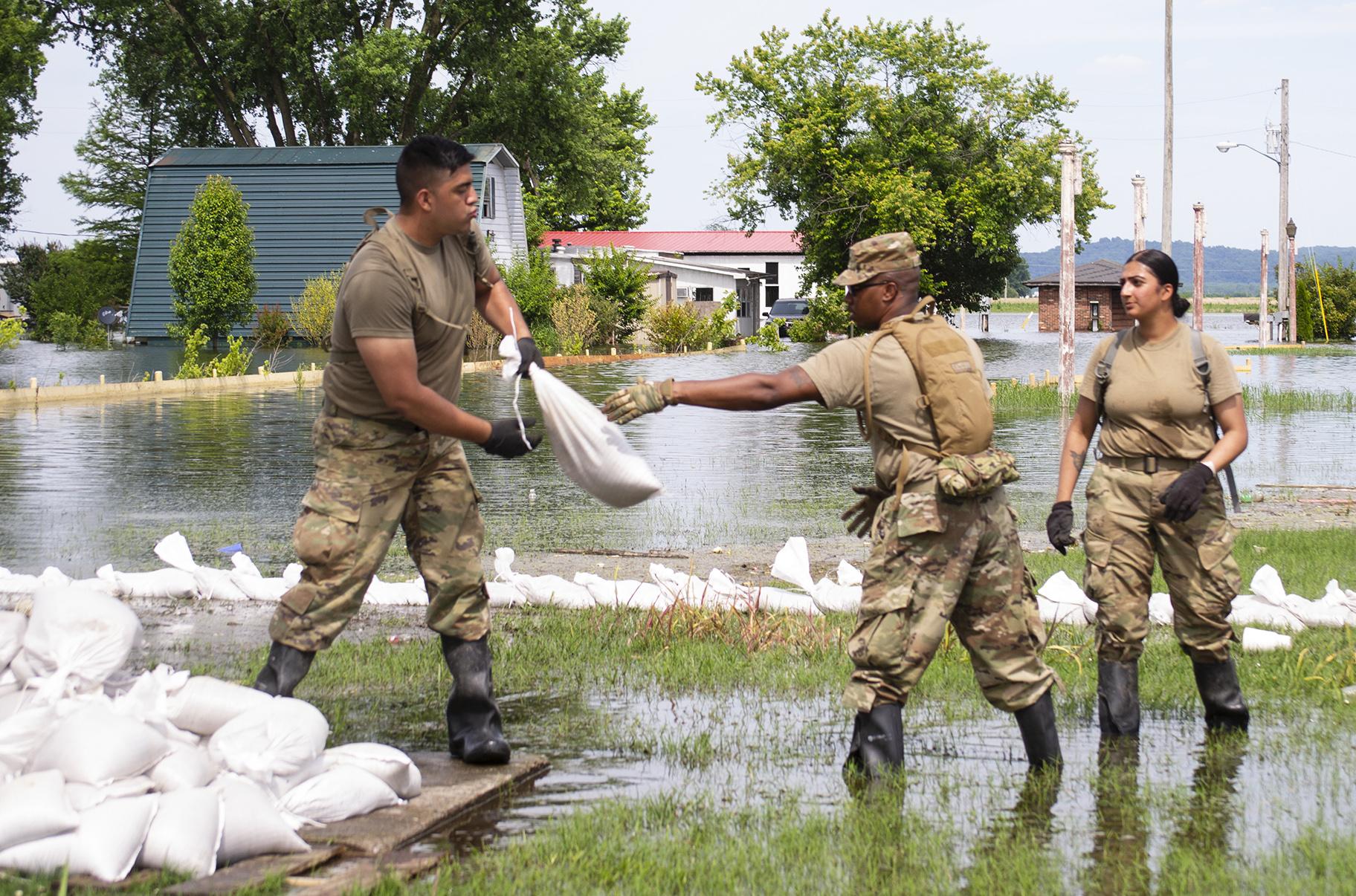 Illinois National Guard soldiers move sandbags through flood waters at East Cape Girardeau, Illinois, on June 12, 2019, as they construct a sandbag levee to control flooding in the community. (Barbara Wilson / Illinois National Guard) 