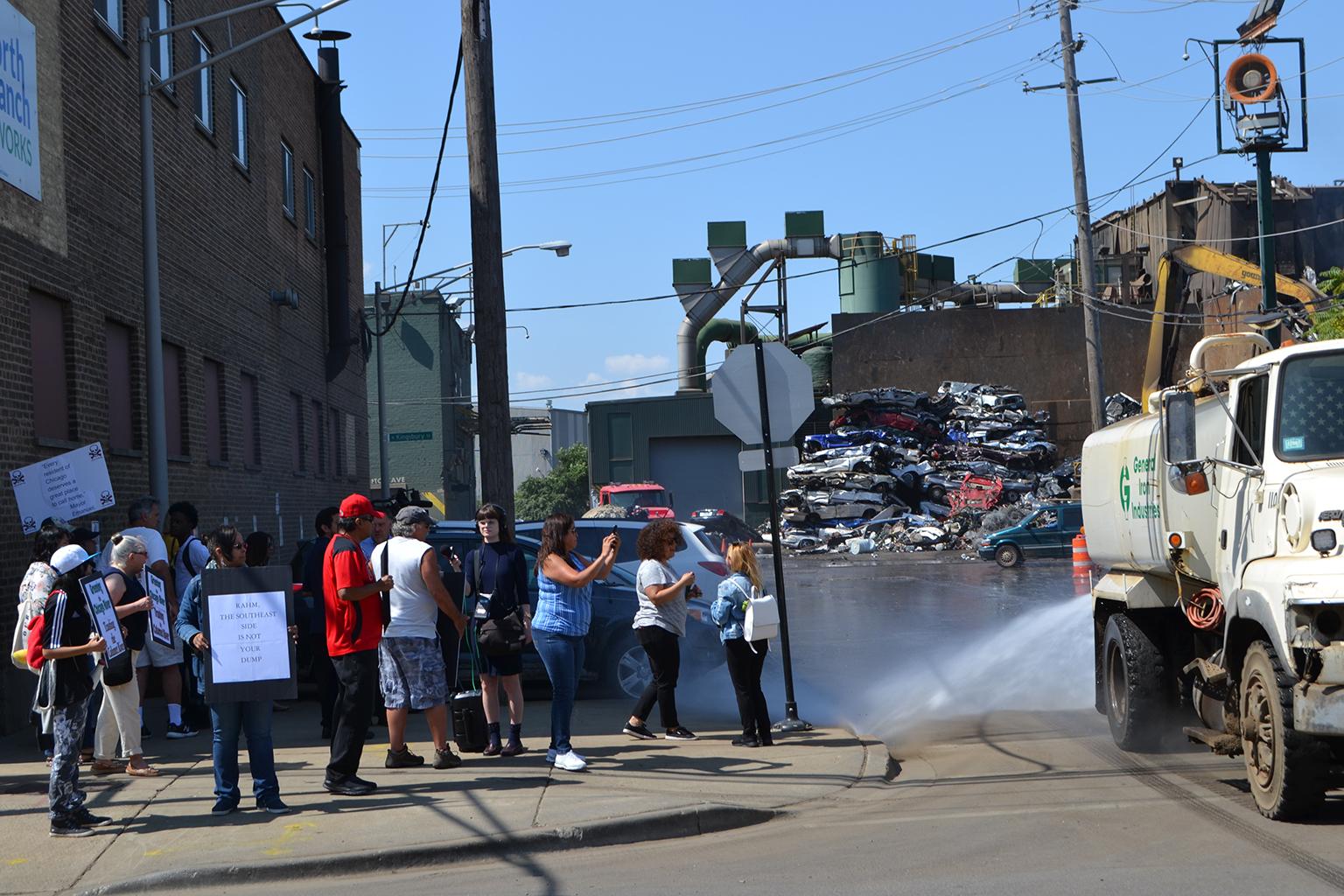 A water-spraying truck operated by General Iron drives past protesters on Monday, July 30, 2018. (Alex Ruppenthal / Chicago Tonight)
