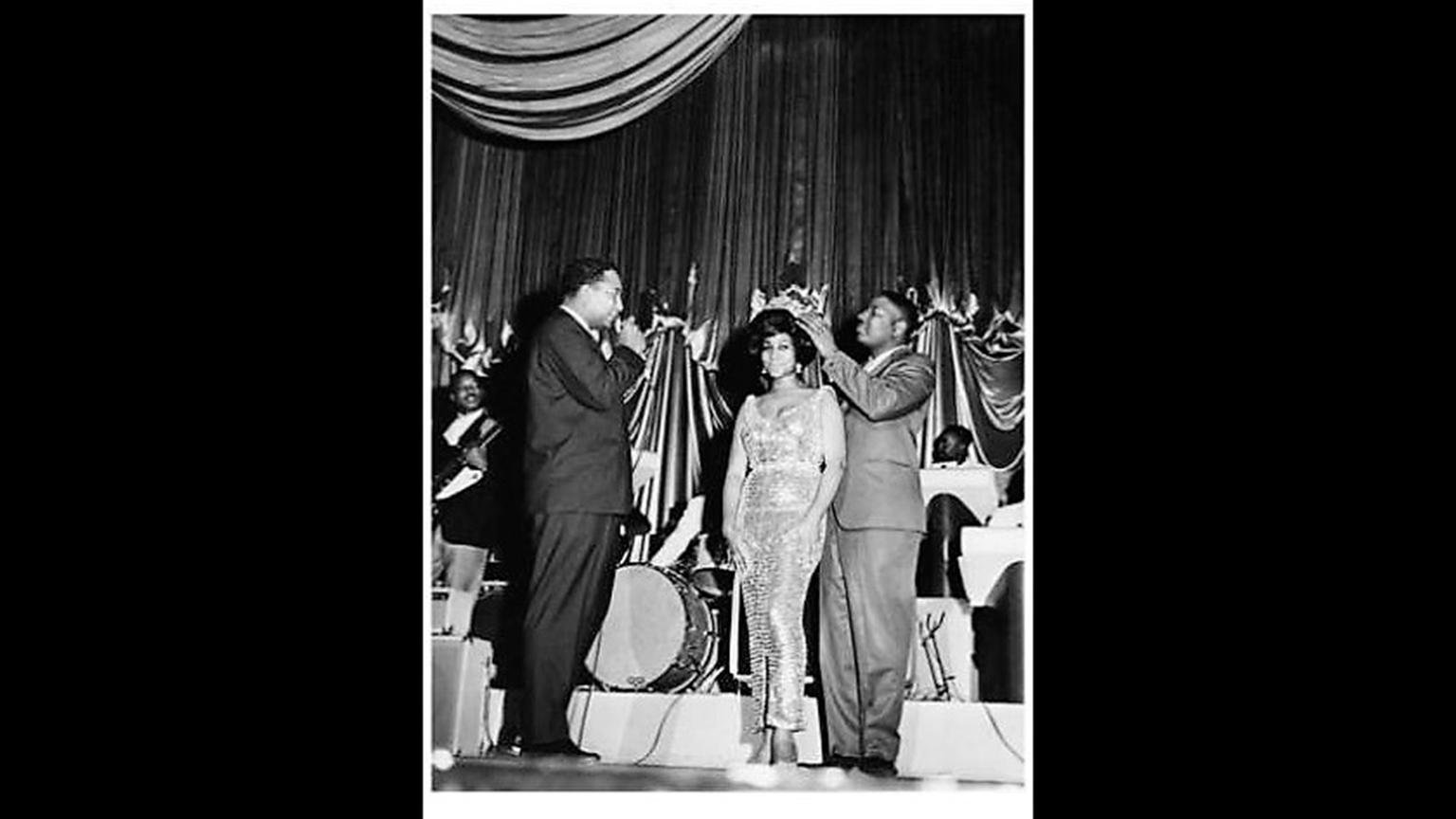 Aretha Franklin is crowned by Pervis Spann at the Regal Theater in May 1964 while Rodney Jones watches. (Courtesy of Jet Magazine)