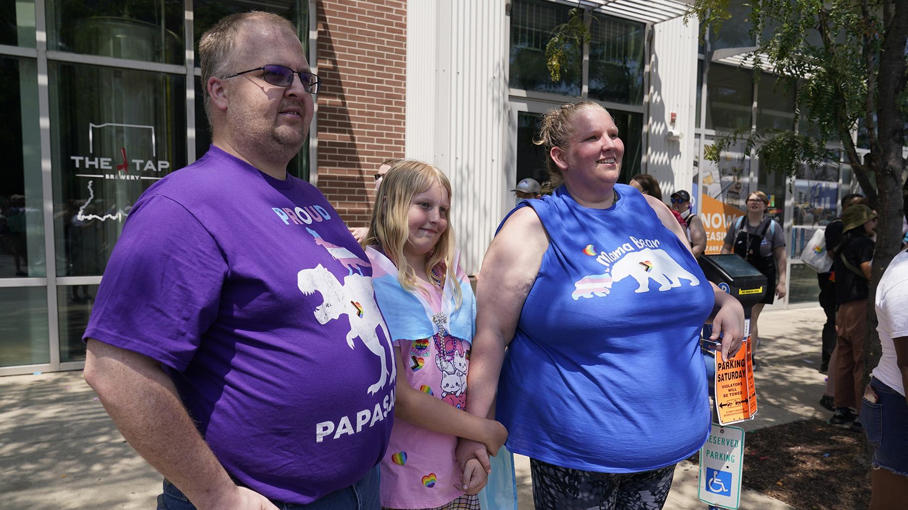 Flower Nichols, middle, watches the Pride Parade with her parents Kris and Jennilyn Nichols, Saturday, June 10, 2023, in Indianapolis. (AP Photo / Darron Cummings)