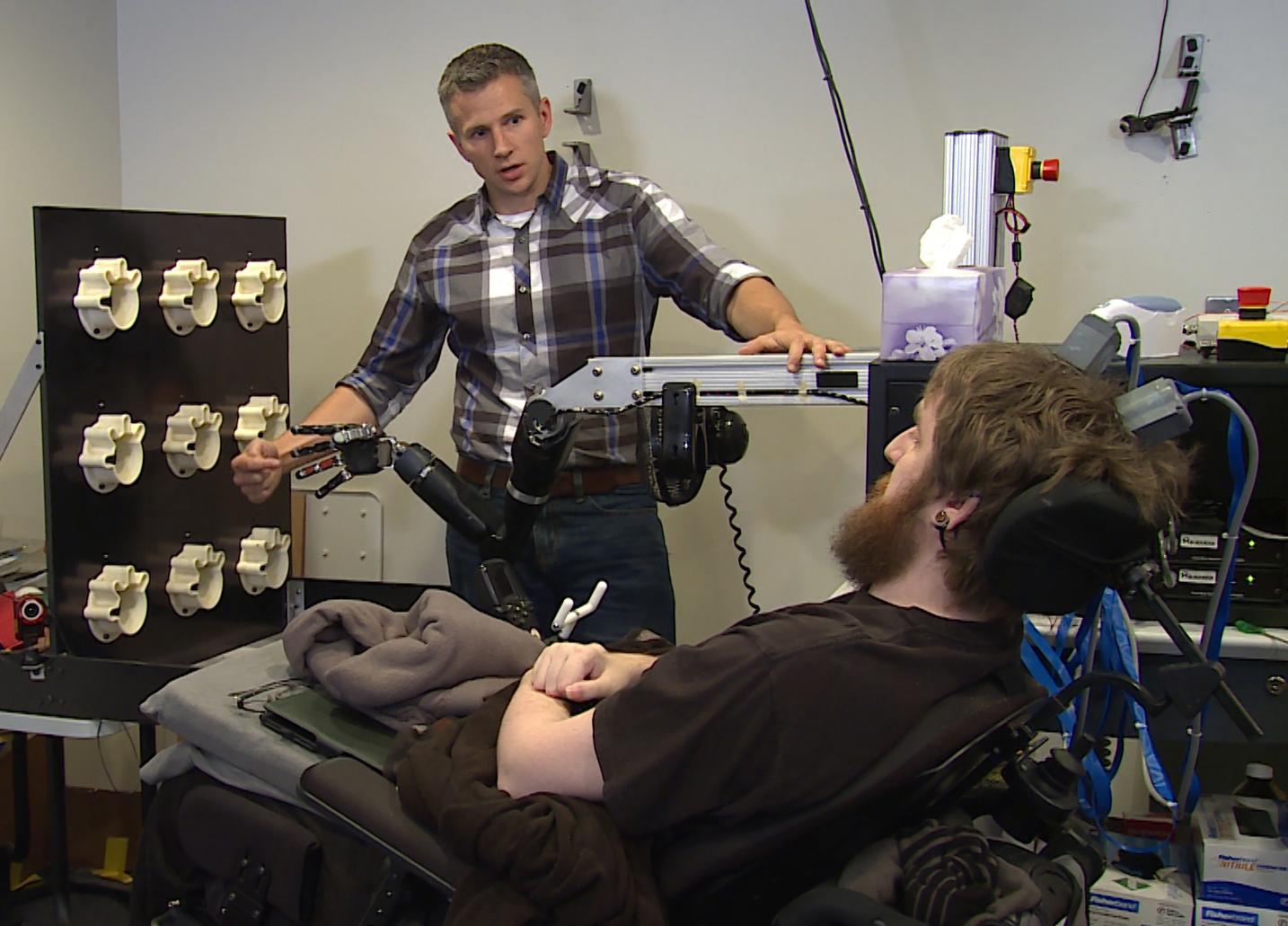 Rob Gaunt from the University of Pittsburgh prepares Nathan Copeland, who was paralyzed in 2004, for a brain computer interface sensory test using a robotic arm. (UPMC / Pitt Health Sciences Media Relations)