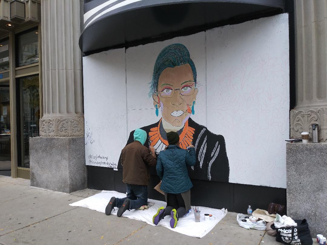 Artists Rachel Lechocki, right, and Andrew Rehs work on a mural of Ruth Bader Ginsburg on Michigan Avenue on Sunday, Oct. 25, 2020. (Annemarie Mannion / WTTW News)