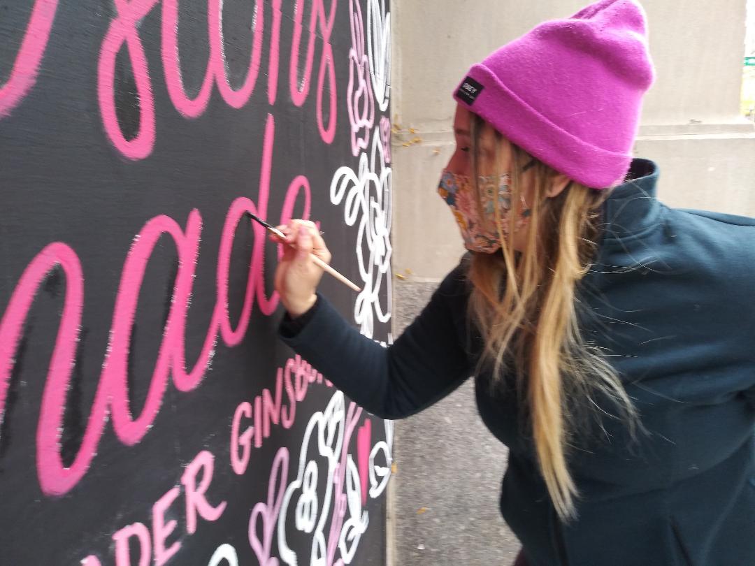 Artist Cristina Vanko hand-letters a Ruth Bader Ginsburg quote on a mural Sunday, Oct. 25, 2020. (Annemarie Mannion / WTTW News)