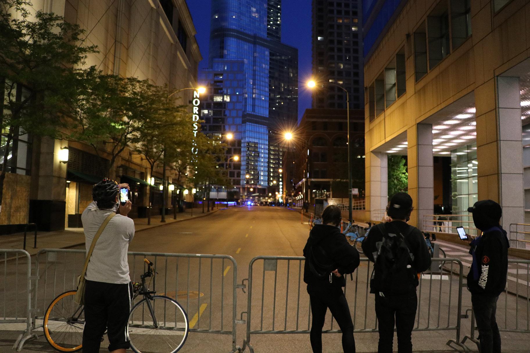 Onlookers photograph the police presence on Wabash Avenue behind a barricade. (Evan Garcia / WTTW News)