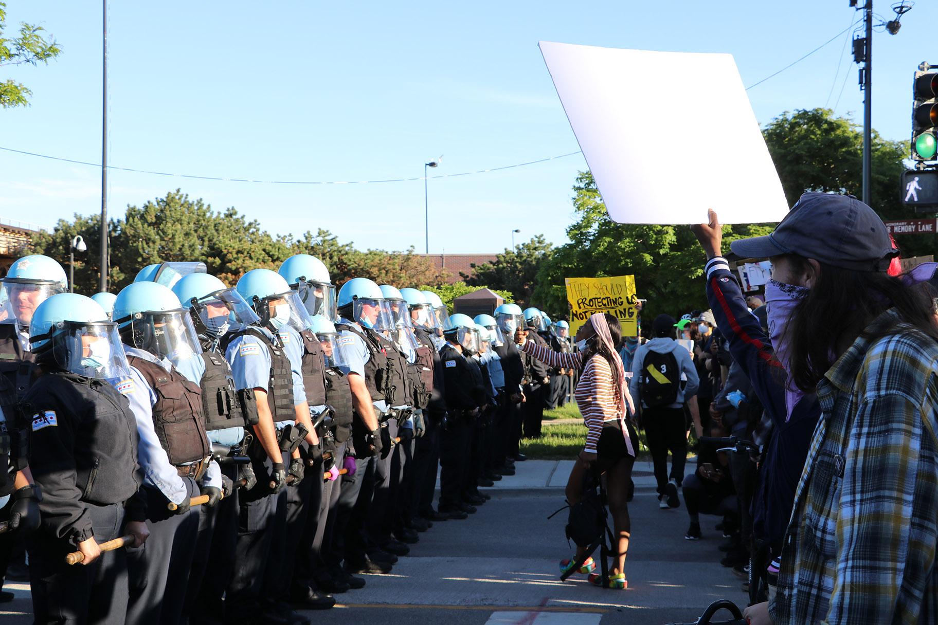Protesters yell at a line of police officers at State and 35th streets, about 3 miles south of the Loop, where police set up a blockade. (Evan Garcia / WTTW News)