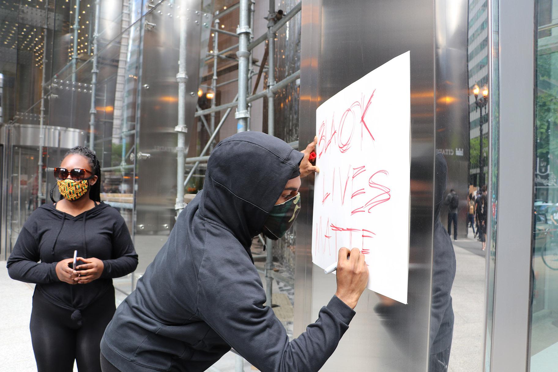 Khalladi Taylor, 23, of Edgewater, draws a Black Lives Matter sign during the protest. “I’m a black man and it affects me every time I see things like George Floyd,” Taylor said. “And it’s not just George Floyd, it’s a bunch of cases across not just this month or this year, that affect me personally. And I feel like it happens here in this city as well, so that’s why I need to be out here with my people.” (Evan Garcia / WTTW News)