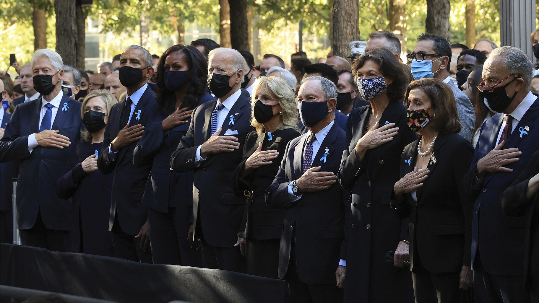 (L-R)  former President Bill Clinton, former First Lady Hillary Clinton, former President Barack Obama, former First Lady Michelle Obama, President Joe Biden, First Lady Jill Biden, former New York City Mayor Michael Bloomberg, Bloomberg's partner Diana Taylor, Speaker of the House Nancy Pelosi and Senate Minority Leader Charles Schumer stand for the national anthem during the annual 9/11 Commemoration Ceremony at the National 9/11 Memorial and Museum Sept. 11, 2021 in New York. (Chip Somodevilla / AP)