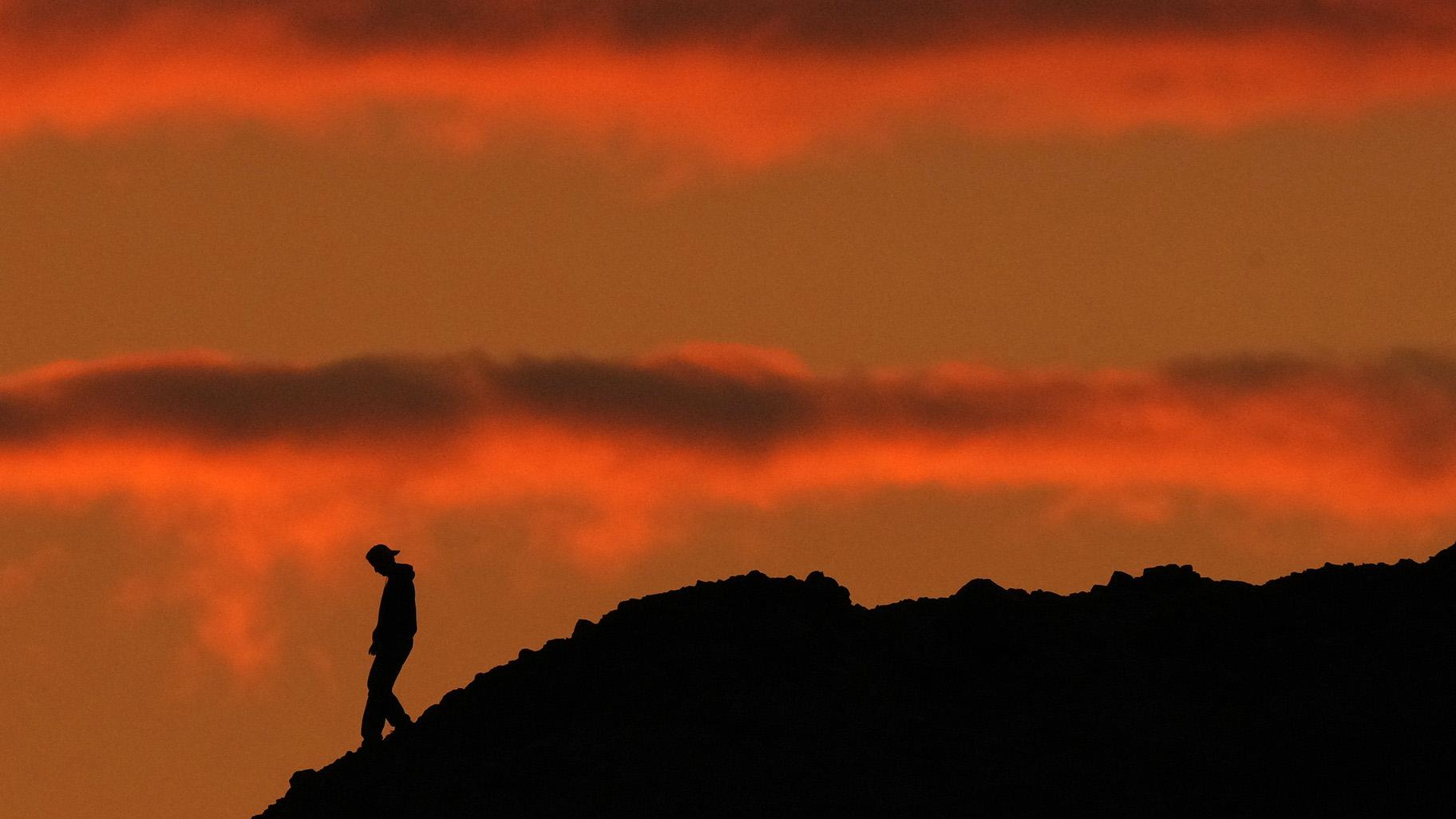 A person is silhouetted against the sky at sunset at Papago Park in Phoenix on Thursday, March 2, 2023. (AP Photo / Charlie Riedel)