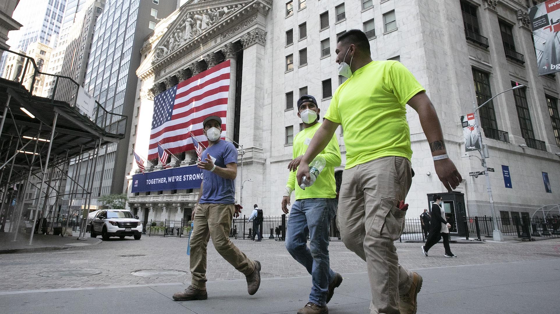 Workers wearing masks walk by the New York Stock Exchange during the coronavirus pandemic, Thursday, July 9, 2020, in New York. (AP Photo/Mark Lennihan)