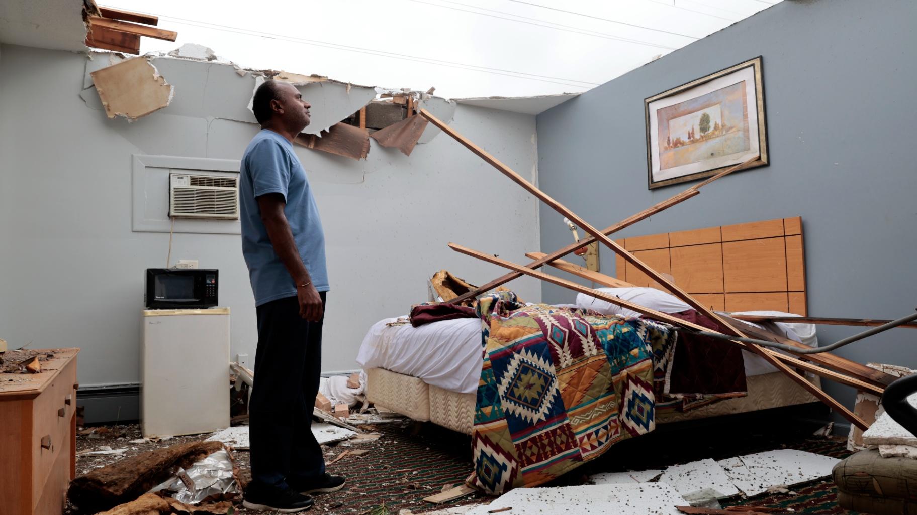 With the roof blown off by severe winds, Brian Patel, owner of the Skyline Motel in the suburban town of McCook, Ill., for the past 30 years, surveys storm damage in one of the motel rooms, Thursday, July 13, 2023. (Antonio Perez / Chicago Tribune via AP)