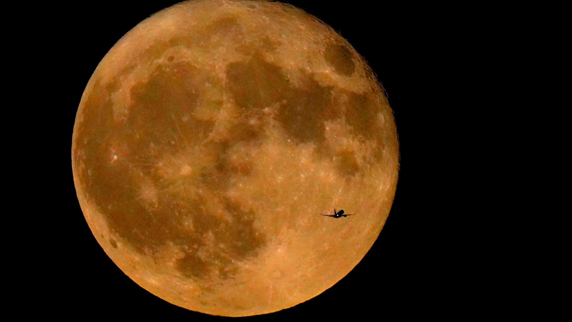 FILE - A commercial airliner flies Northwest across Lake Michigan in front of the "Full Buck" supermoon, the first of four supermoons in 2023, July 3, 2023, in Chicago. (Charles Rex Arbogast / AP Photo, File)